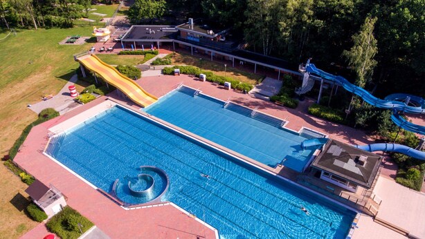 Vista aerea di una grande piscina con uno scivolo e un’area acquatica.