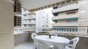 A balcony with a round table and white chairs, overlooking a residential area with multi-story buildings. - Estornell With 2 Bedrooms and 1 Bathrooms (Daimuz)