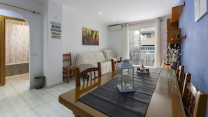 A dining area with a long table, chairs, and a decorative lantern. There is a sofa and a small trash bin in the background. - Estornell With 2 Bedrooms and 1 Bathrooms (Daimuz)