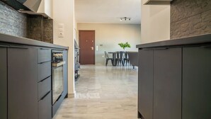 Una cocina moderna con armarios oscuros, un salpicadero de piedra y suelo de mármol.