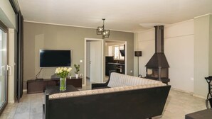 Una sala de estar moderna con sofá, televisión, chimenea y comedor.