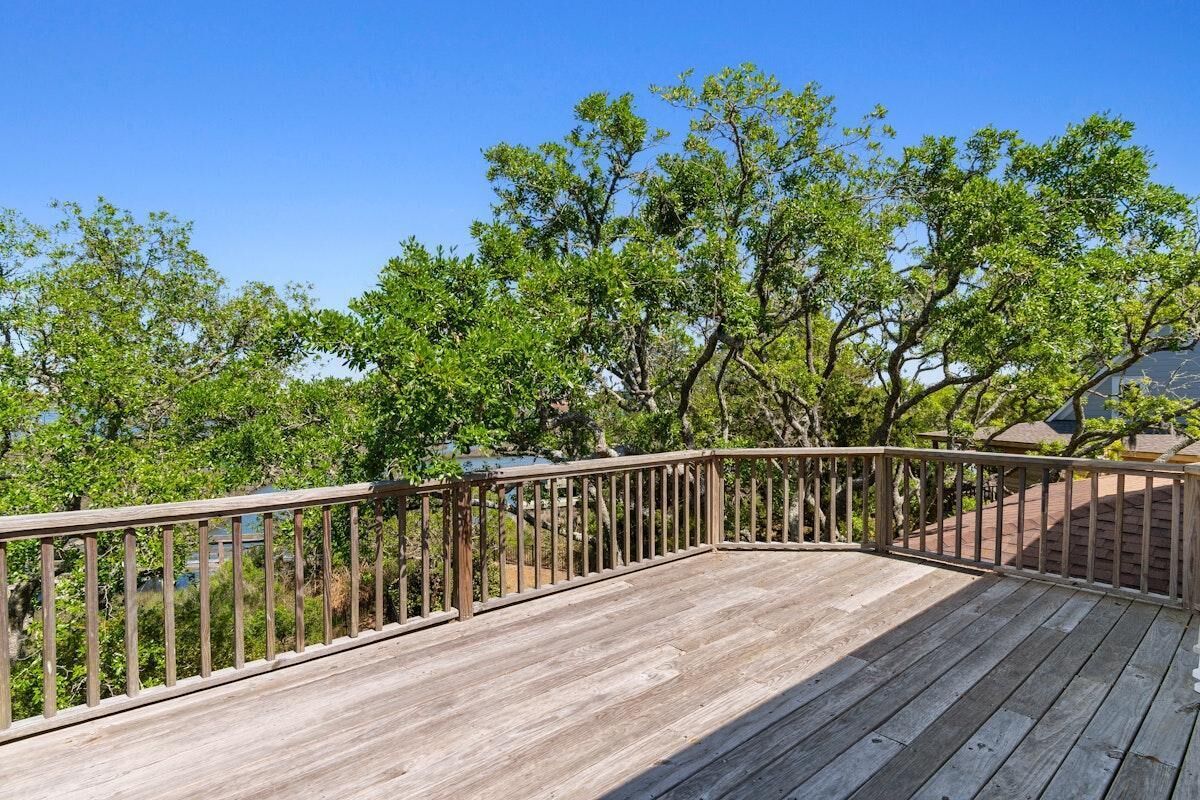 A wooden deck with a railing, surrounded by trees.