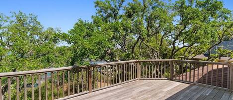 A wooden deck with a railing, surrounded by trees.