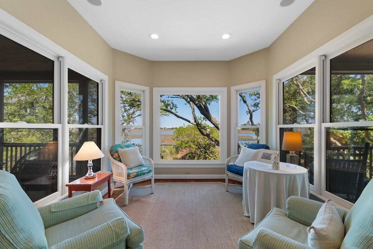 A cozy room with large windows, a view of trees, a small table, and two chairs.