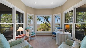 Una habitación acogedora con amplias ventanas, vista a árboles, una mesita y dos sillas.