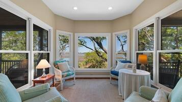 A cozy room with large windows, a view of trees, a small table, and two chairs.