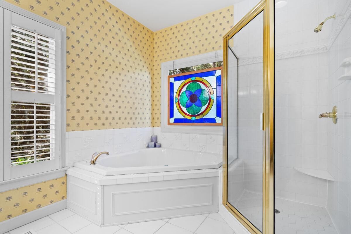 A bathroom with a large bathtub, a shower, and a stained glass window.