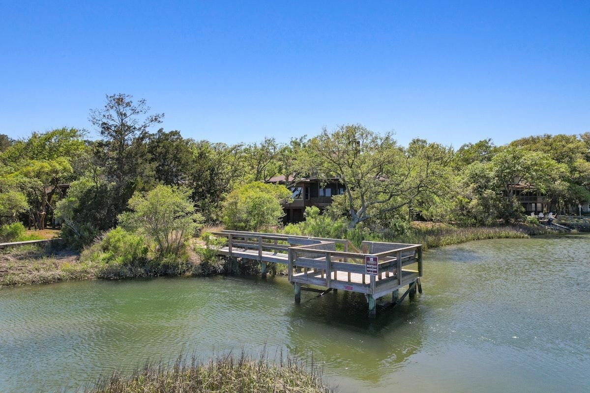 A wooden dock over water with a building in the background.