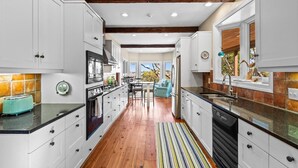 Una cocina moderna con armarios blancos, piso de madera y alfombra a rayas.