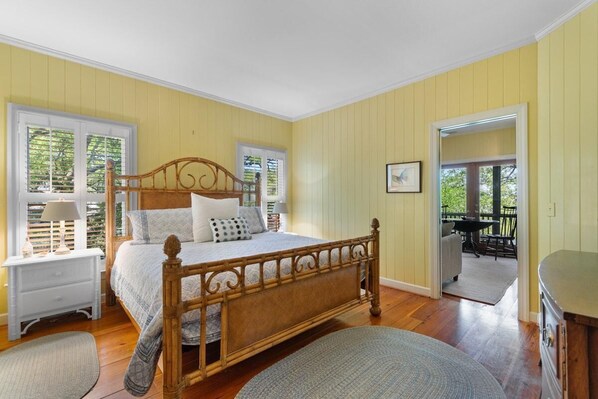 Une chambre avec un lit en bois, une table de chevet, une commode et une vue sur l’extérieur.