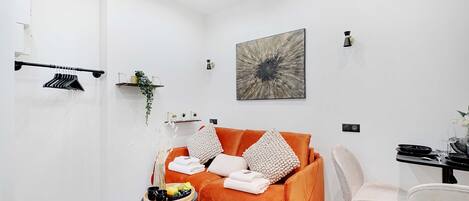 Ein modernes Wohnzimmer mit einer Couch, einem Esstisch und einer Kaffeemaschine.