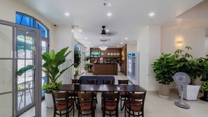 A dining area with a large table and chairs, a bar area with a counter and various items, and potted plants. - Alba Sand Hotel Phu Quoc (Phu Quoc)