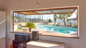A room with a view of an outdoor swimming pool, a window, a speaker, and a small table. - MOLINO DE LOS CARDENES 1911 (Montoro)