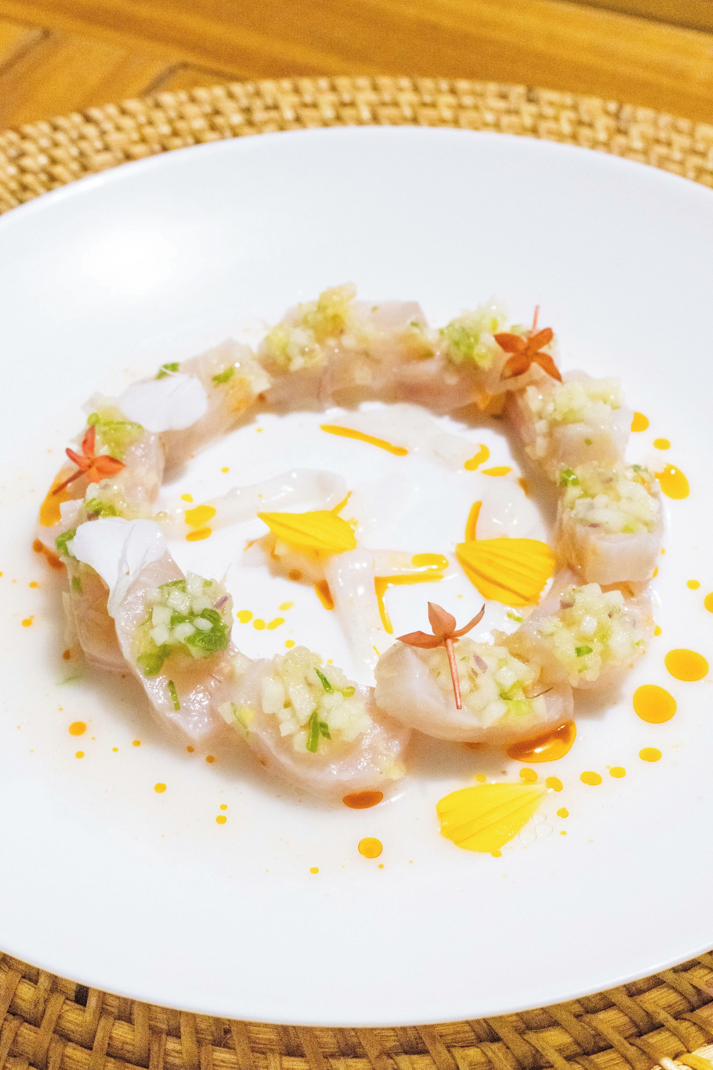 A white plate with a seafood dish, garnished with herbs and yellow sauce.