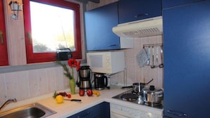Una cocina con gabinetes azules, una estufa blanca, un microondas y varios utensilios de cocina.