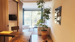 A modern interior with a wooden dining table, a potted plant, and a view of a balcony with a white chair. - Peaceful, central apartment in a quiet, tree-lined street, rare in Casablanca. (Casablanca)