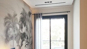 A modern hotel room with a large bed, a nightstand, a wall mural, and a sliding glass door to the balcony. - Peaceful, central apartment in a quiet, tree-lined street, rare in Casablanca. (Casablanca)