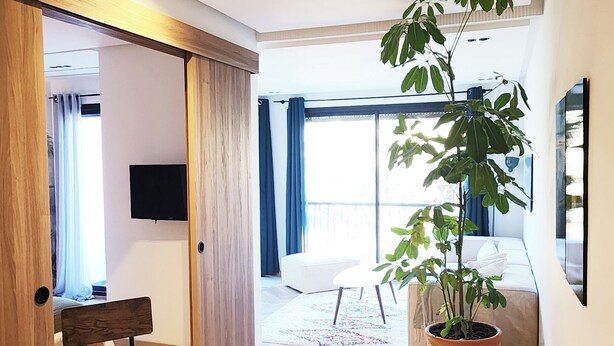 A modern living room with a wooden dining table, a large potted plant, and a sofa. - Peaceful, central apartment in a quiet, tree-lined street, rare in Casablanca. (Casablanca)