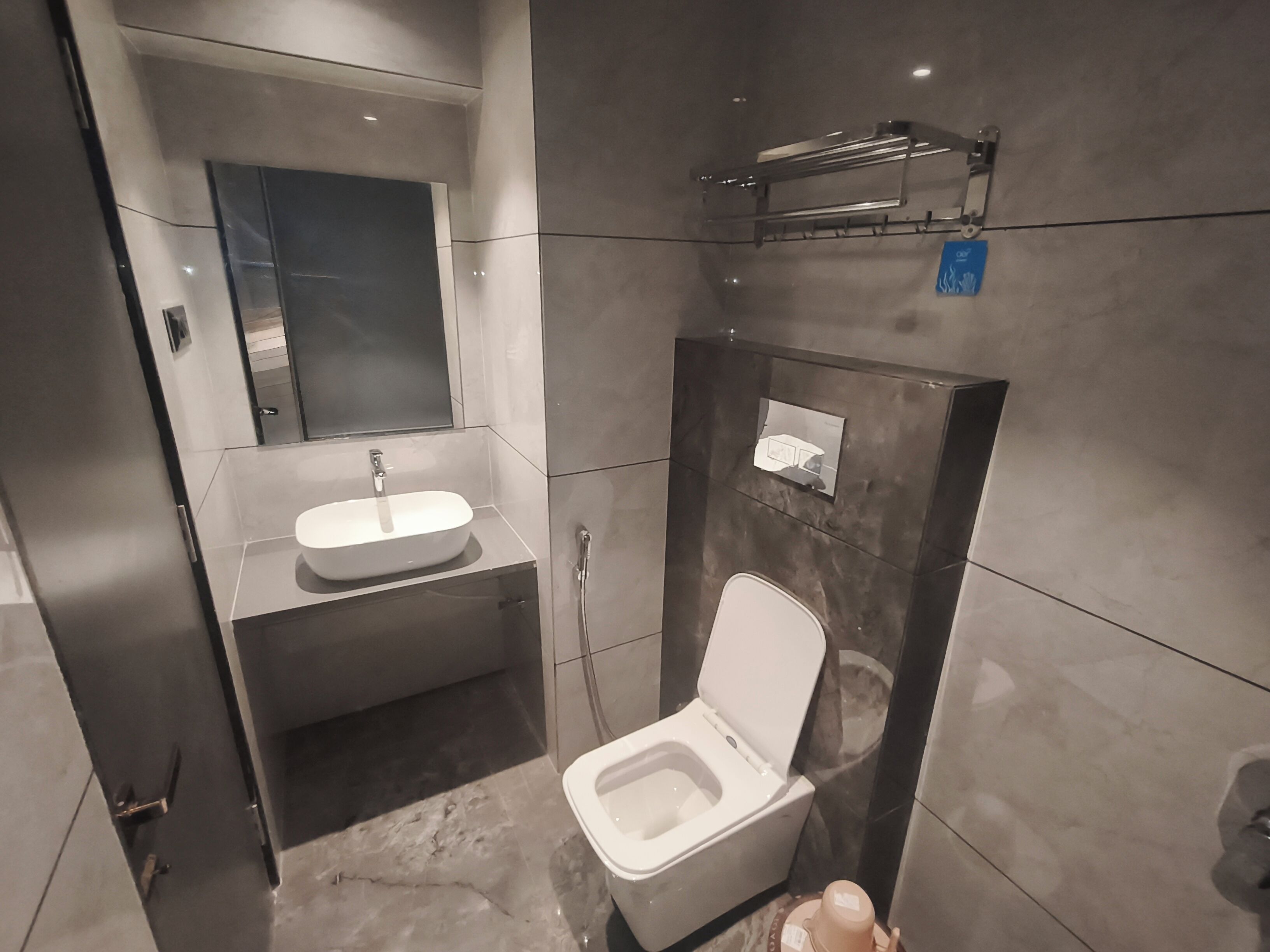 A modern bathroom with a white sink, a toilet, and a mirror above the sink.