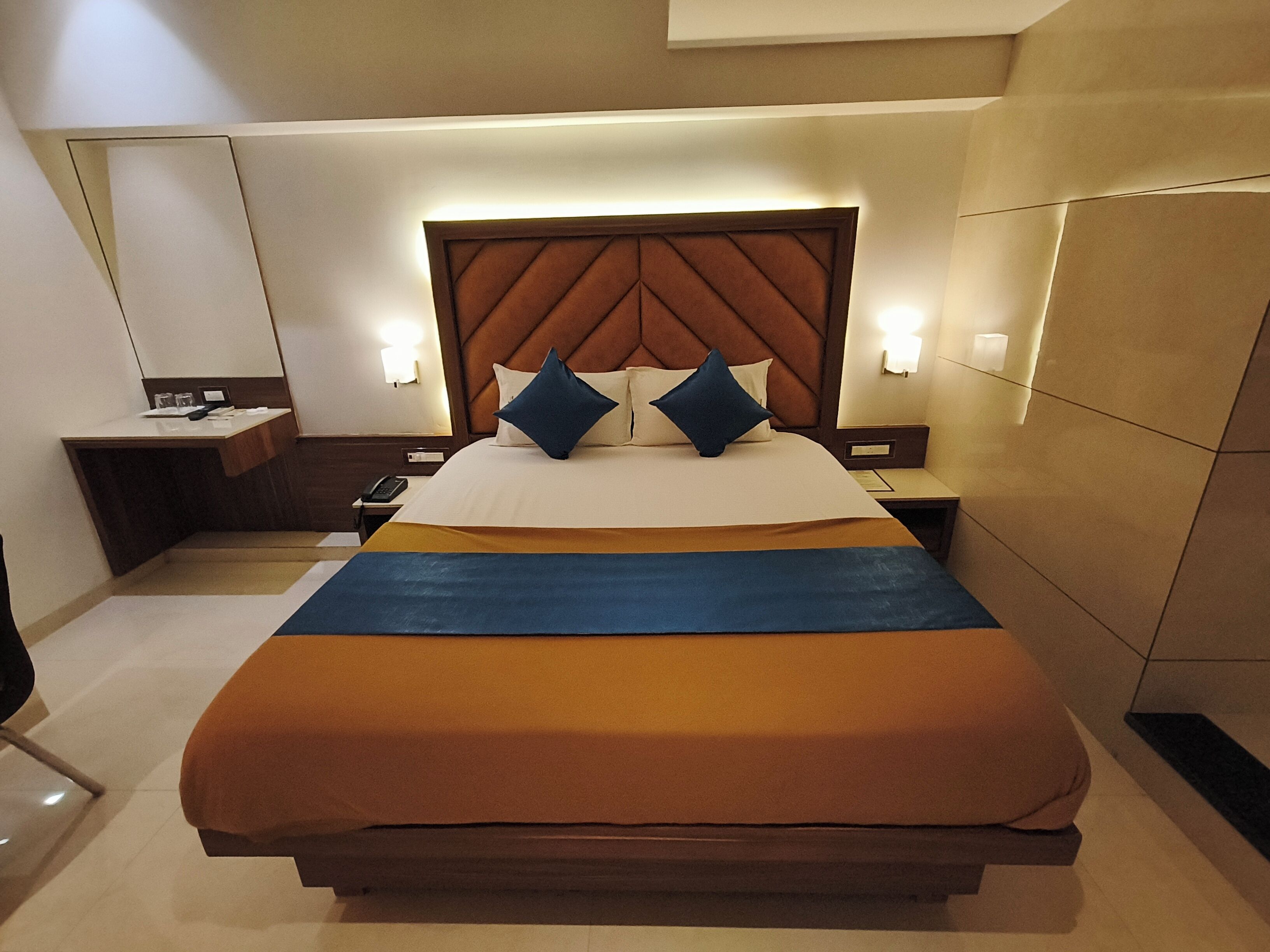 Ein Hotelzimmer mit einem großen Bett, einem Nachttisch und einer Wandleuchte.