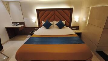 A hotel room with a large bed, a nightstand, a bedside table, and a wall-mounted light fixture.