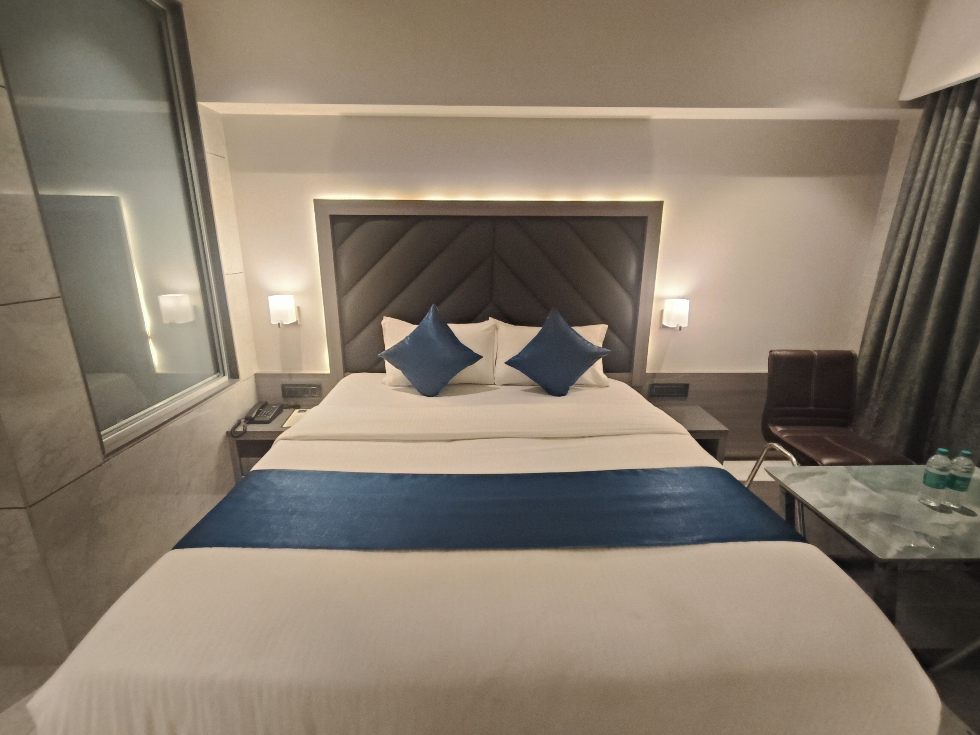 A hotel room with a large bed, two bedside tables, a nightstand, a desk, and a chair.