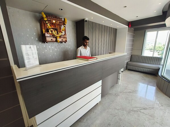 A reception desk with a modern design, a seating area, and a decorative wall. - Hotel Nakshatra Residency (Bhiwandi)
