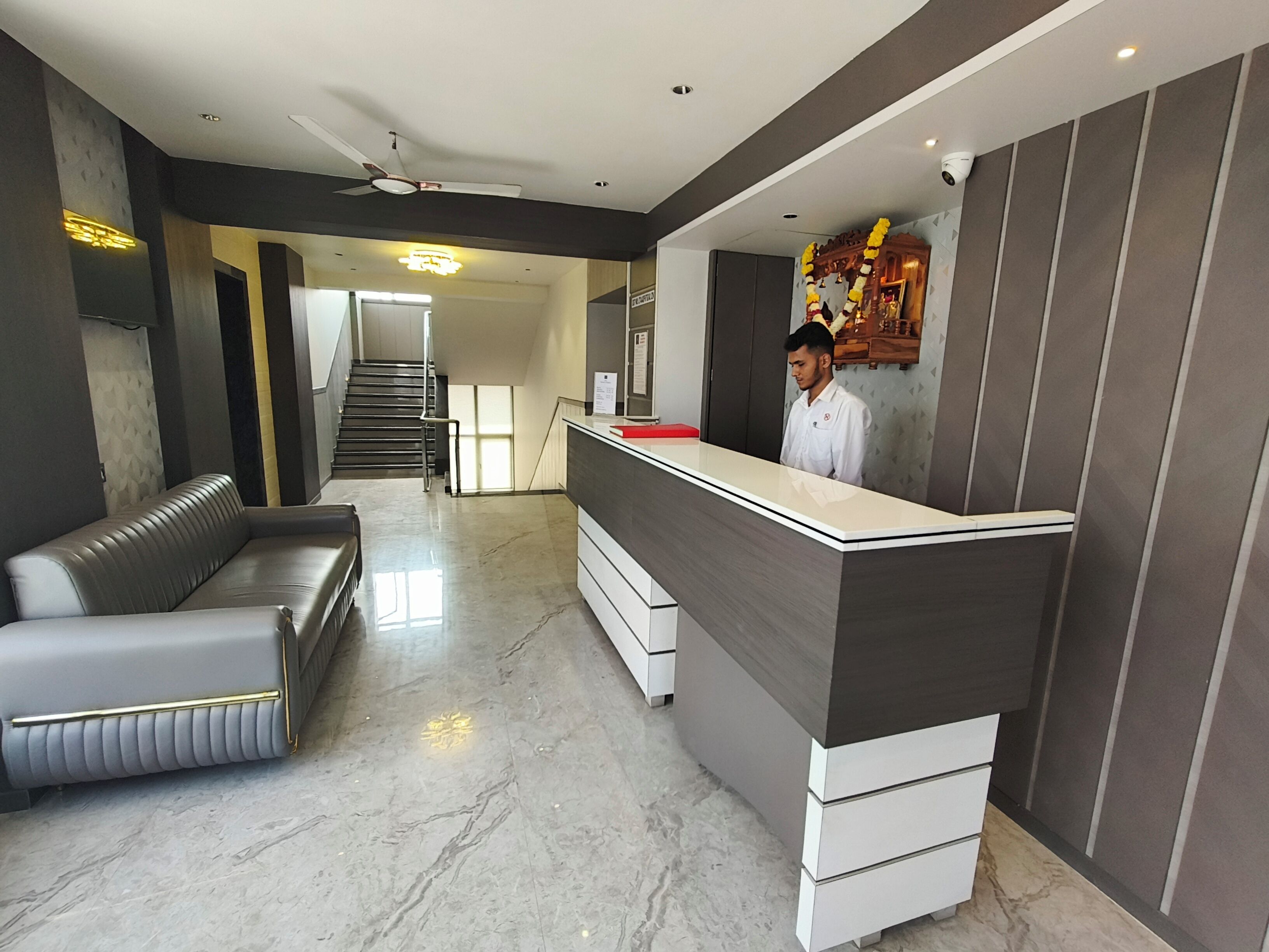 Un área de recepción moderna con mostrador, un sofá y una escalera que conduce a un piso superior.