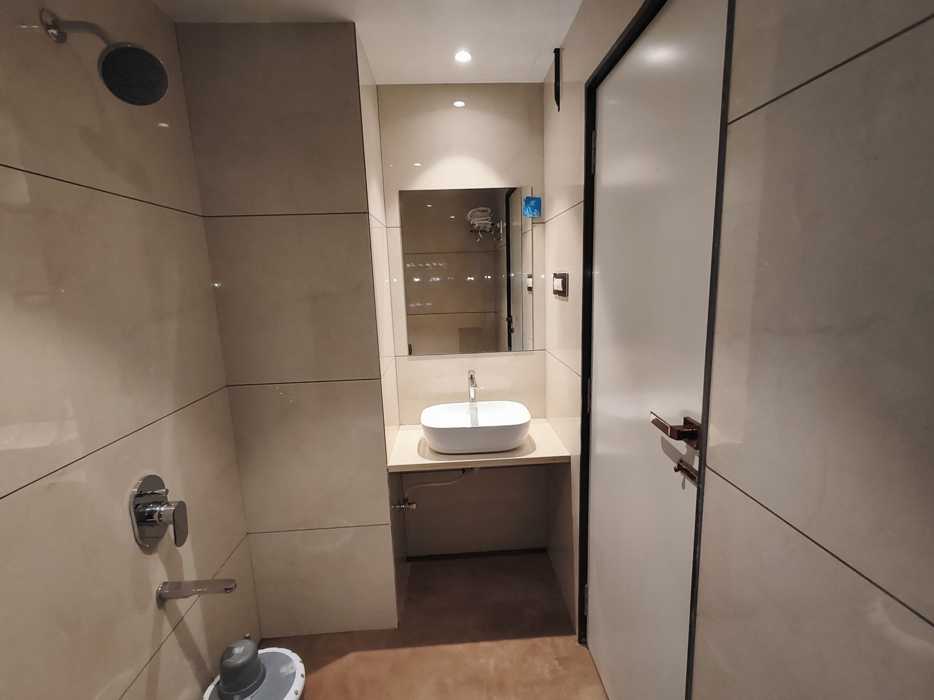 A modern bathroom with a large mirror, a sink, and a shower.