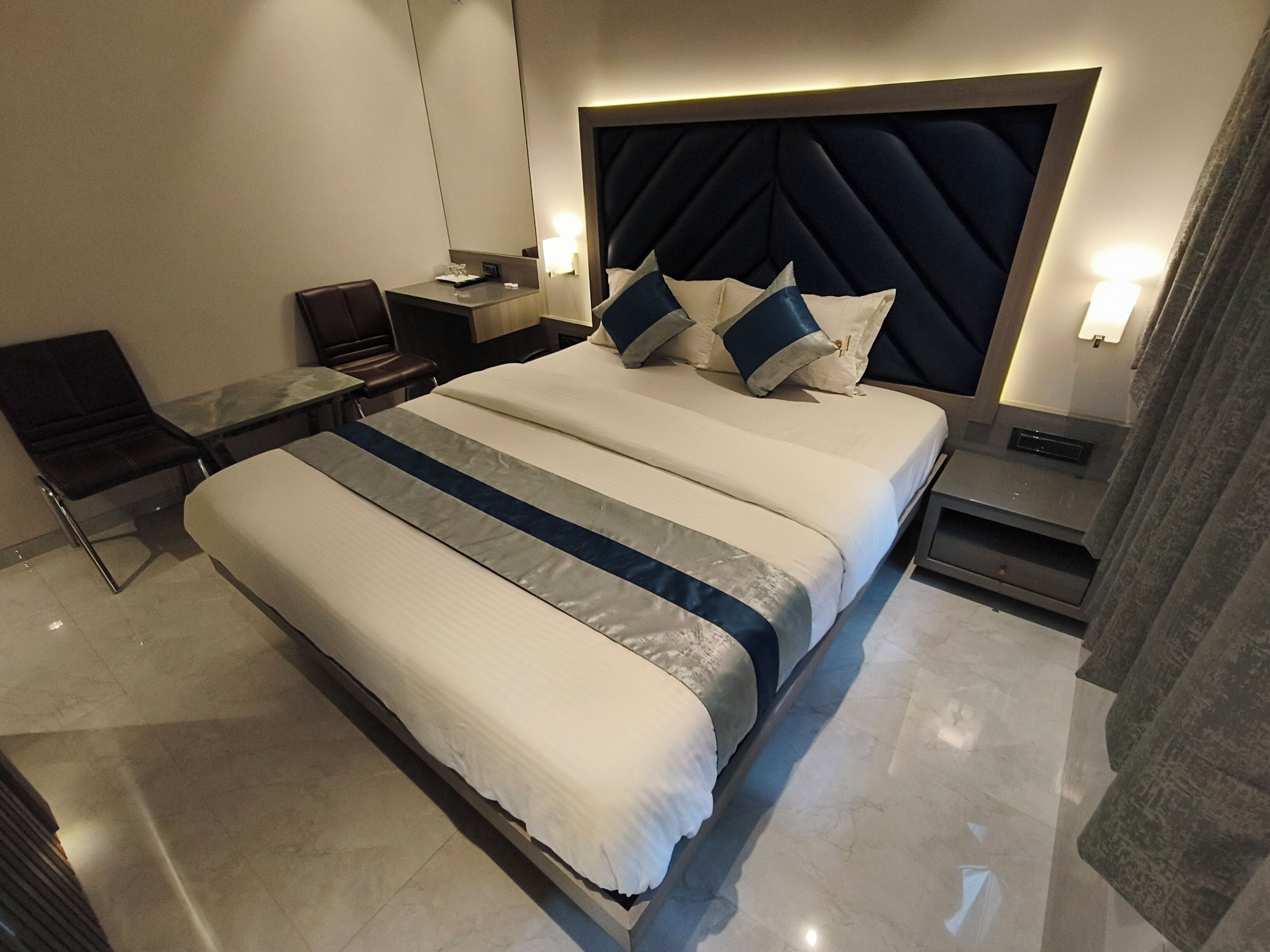 Una habitación de hotel moderna con una cama grande, mesitas de noche, un escritorio y una silla.