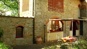 A stone building with a patio area, including a table and chairs, and a large pot. - Holiday Home in Reggello (Reggello)