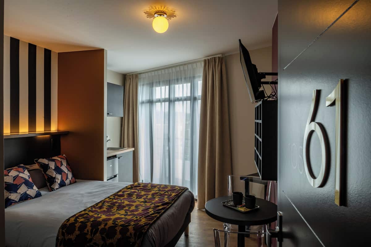 A hotel room with a bed, a desk, and a TV.