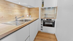 A compact kitchen with a wooden countertop, stainless steel sink, and built-in oven. - Montana Village - appartement rénové, 5 pers (Montana Village)