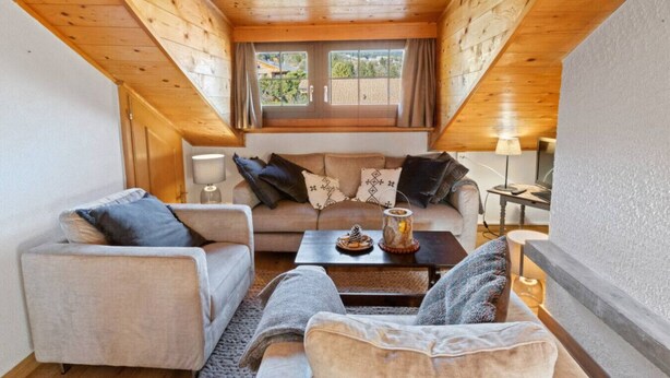 A cozy living room with a high ceiling and wooden beams, furnished with a sofa, armchairs, and a coffee table. - Montana Village - appartement rénové, 5 pers (Montana Village)