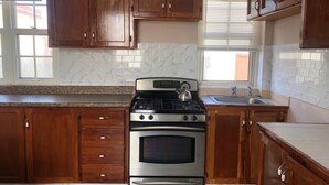 A kitchen with wooden cabinets, a stainless steel stove, and a marble backsplash.