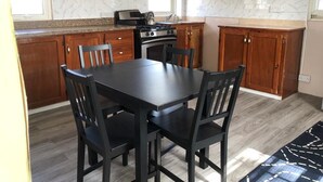 A kitchen with wooden cabinets, a black dining table, and chairs.