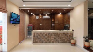 A reception area with a wooden reception desk, a digital display, and a Coca-Cola refrigerator.