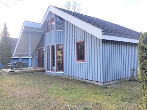Une maison moderne avec un toit en pente, de grandes fenêtres et un patio couvert.