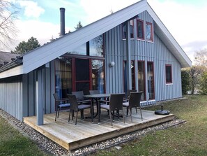 Une maison moderne dotée d’une terrasse, de grandes fenêtres et d’une cheminée.