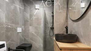 A modern bathroom with a black bidet, a wooden vanity, and a glass shower enclosure.