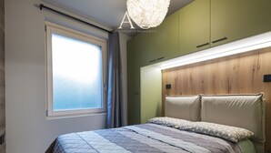 A bedroom with a bed, a window, and a green wardrobe.
