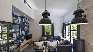 Uma sala de estar moderna com um sofá, cadeiras, lareira e um grande quadro abstrato na parede.