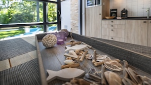 Cozinha com armários de madeira, bancada com eletrodomésticos e vista para o exterior.