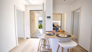 Una cocina moderna con una mesa de comedor, dos sillas blancas y vistas al exterior.