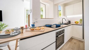 Una cocina moderna con armarios blancos, encimera de madera, una sartén azul y un lavabo.