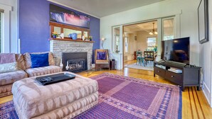 A living room with a fireplace, a television, and a sofa. - Walker’s Delight on Queen Anne (Seattle)