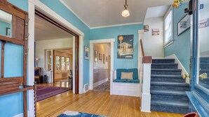 A staircase with a blue carpet leading to a landing with a bench and a painting of a cityscape. - Walker’s Delight on Queen Anne (Seattle)