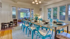 A dining area with a glass table, blue chairs, and a chandelier. - Walker’s Delight on Queen Anne (Seattle)