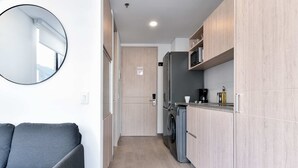 Eine kompakte Küche mit Holzausstattung, einer integrierten Waschmaschine und einem runden Spiegel an der Wand.