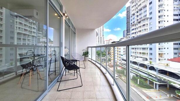 A balcony with a glass railing, a potted plant, and a chair. - w* | Modern 2BR In La Cresta (Panama City)